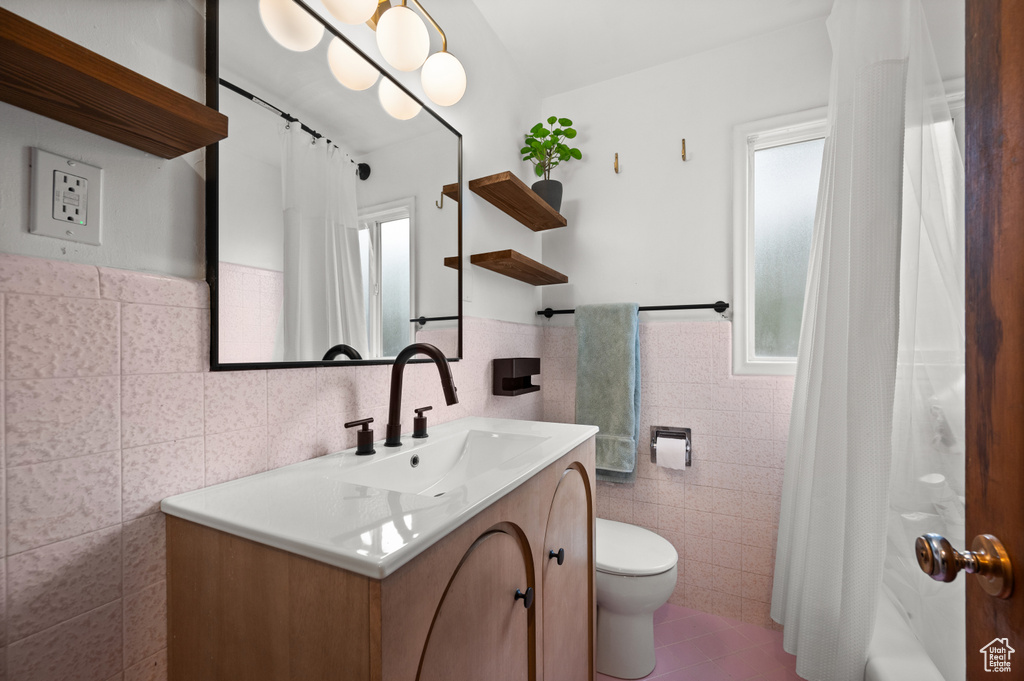 Full bathroom featuring tile walls, tile patterned flooring, toilet, vanity, and a wainscoted wall