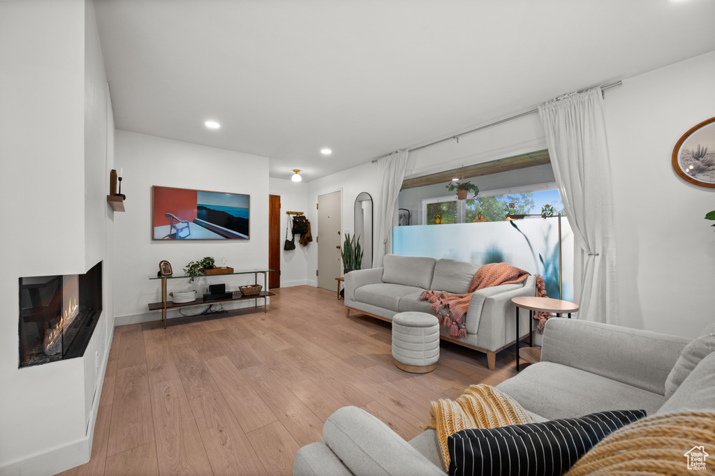 Living room featuring recessed lighting, light wood-style flooring, baseboards, and a multi sided fireplace
