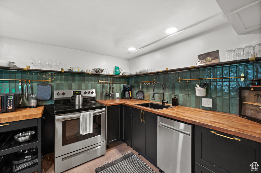 Kitchen featuring butcher block counters, stainless steel appliances, a sink, and backsplash