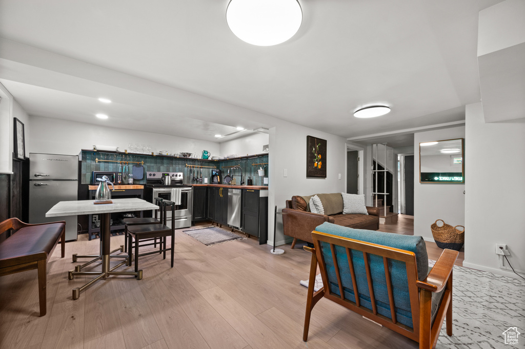 Dining area featuring bar with sink, light wood-type flooring, and recessed lighting
