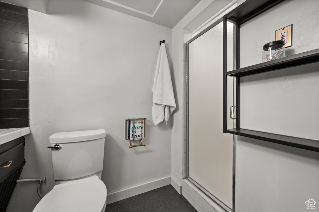 Bathroom featuring toilet, a shower stall, and baseboards