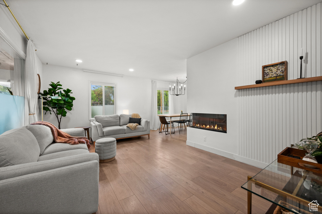 Living area with hardwood / wood-style flooring, recessed lighting, a chandelier, and a glass covered fireplace