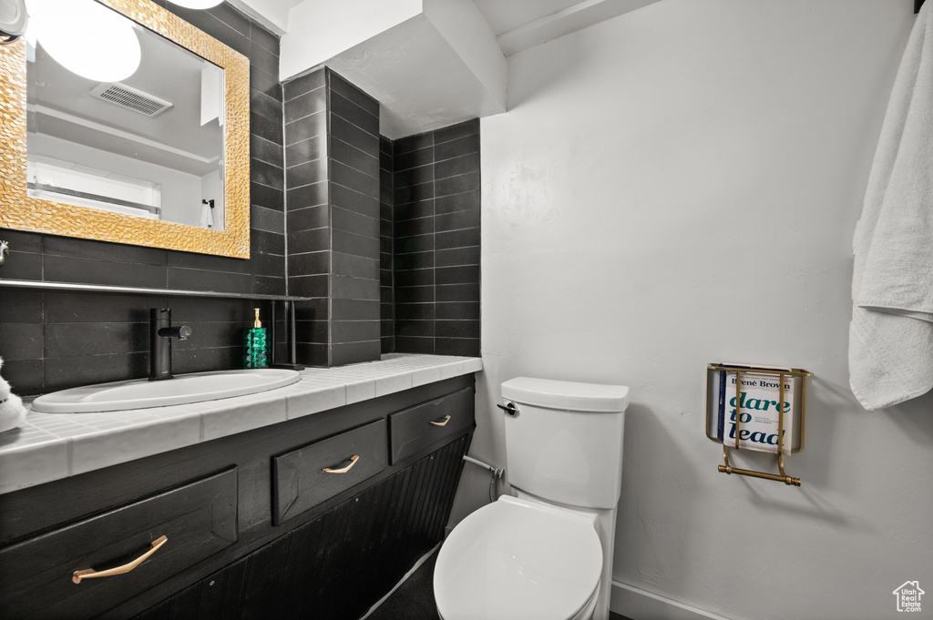 Bathroom featuring decorative backsplash, toilet, vanity, and baseboards