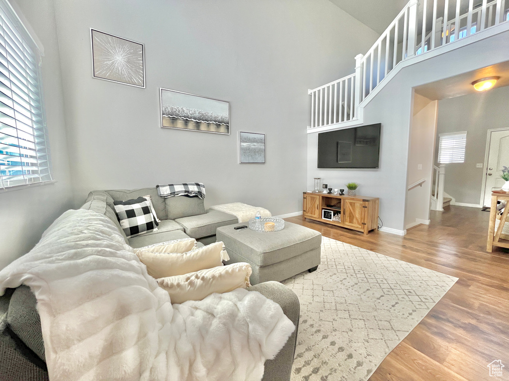 Living room with a towering ceiling, wood finished floors, stairway, and baseboards
