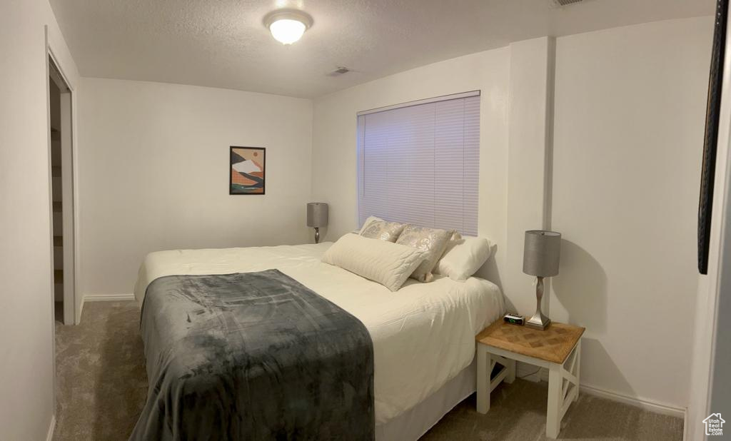 Carpeted bedroom with baseboards and a textured ceiling