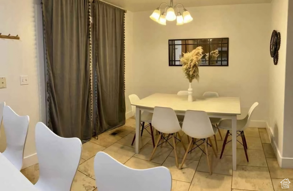 Dining area with a chandelier, light tile patterned floors, and baseboards