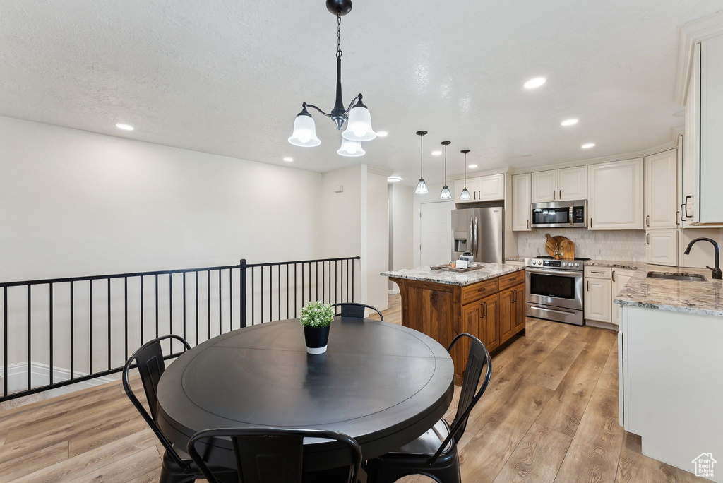 Dining space with light wood-style floors, a chandelier, and recessed lighting