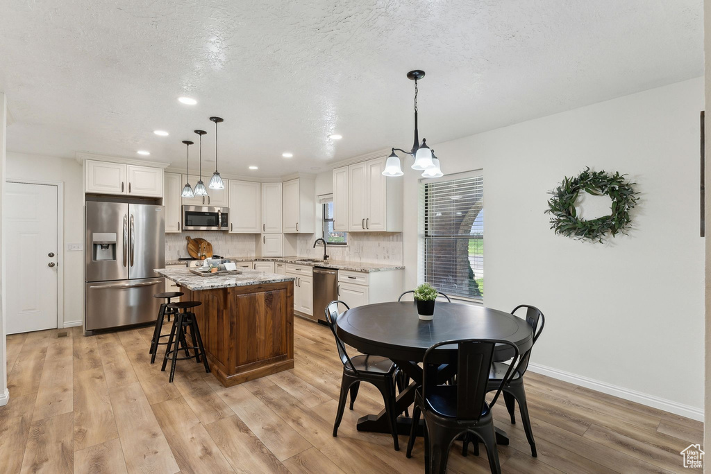 Dining area with light wood finished floors, recessed lighting, and baseboards