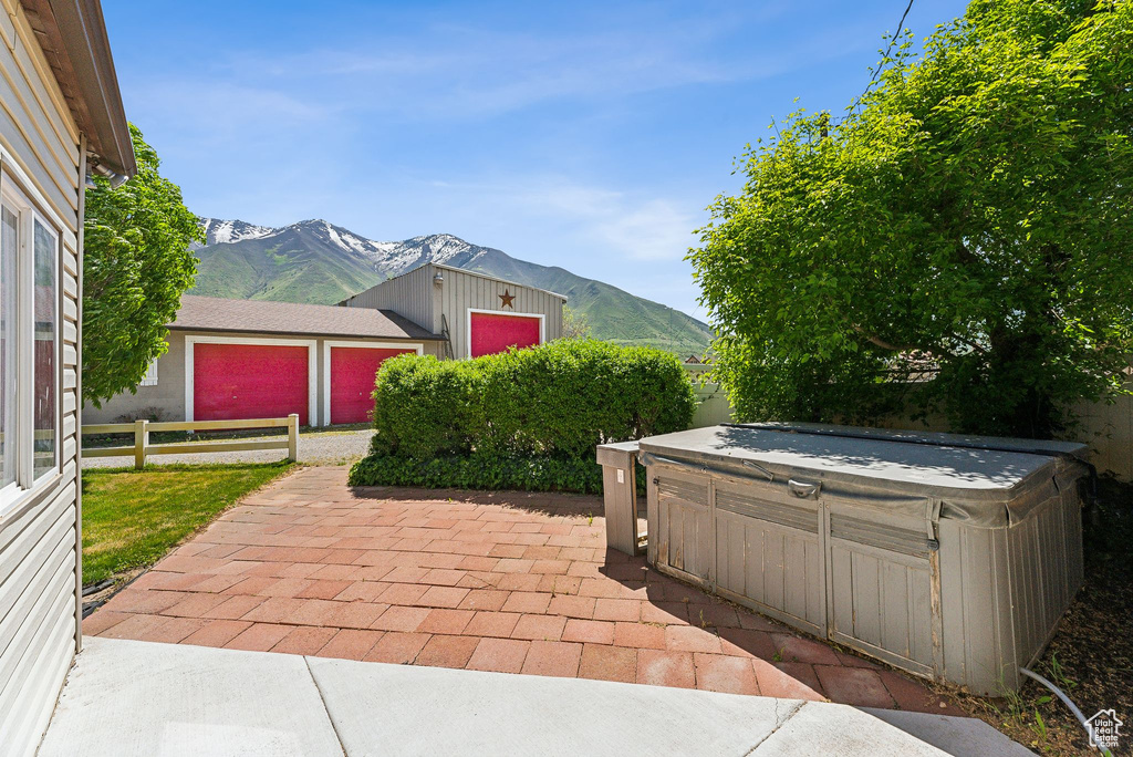 View of patio featuring a hot tub, a mountain view, and fence