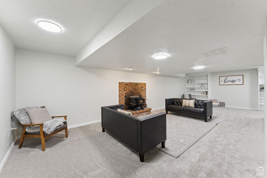 Carpeted living area with baseboards, a wood stove, and a textured ceiling