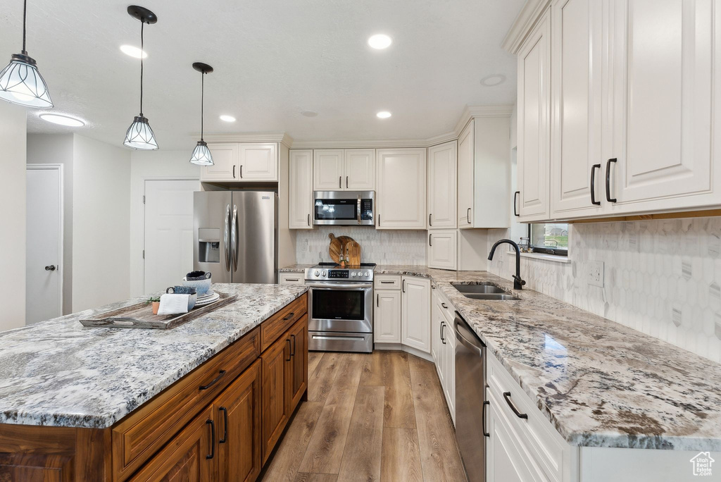 Kitchen with stainless steel appliances, a sink, light wood-type flooring, white cabinetry, and recessed lighting