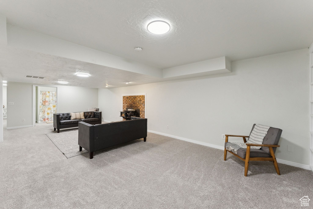 Carpeted living area featuring baseboards, a textured ceiling, and a brick fireplace