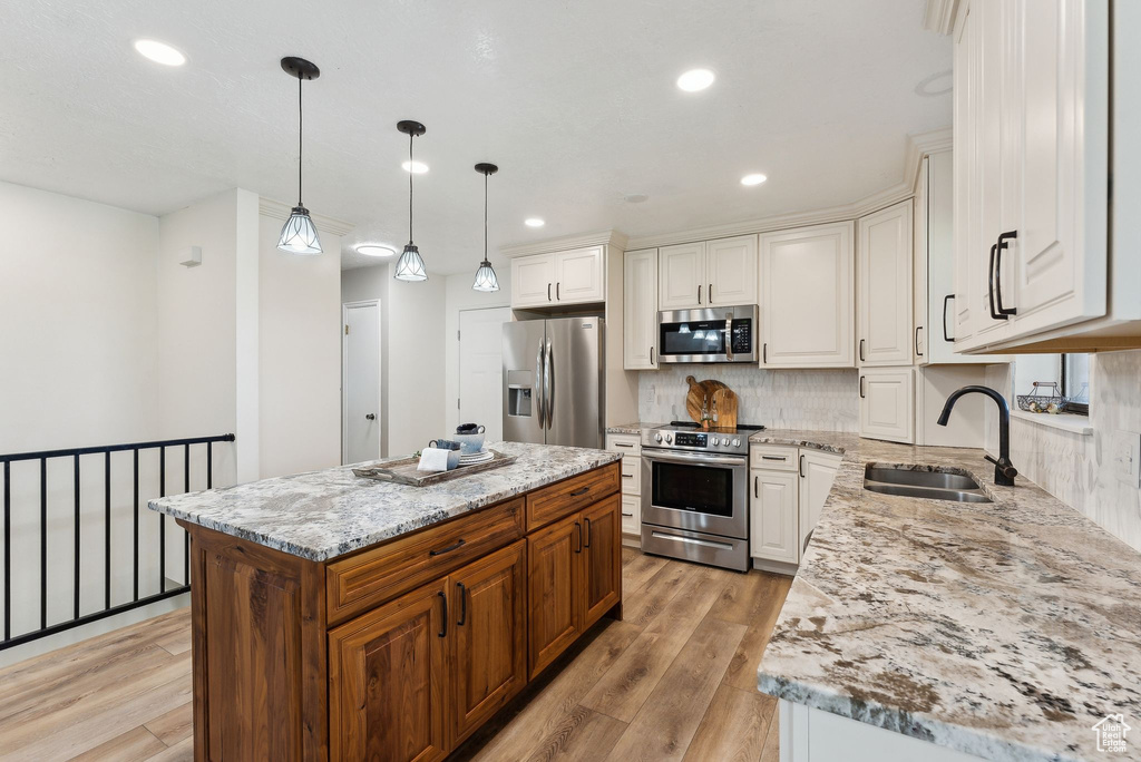 Kitchen featuring appliances with stainless steel finishes, a sink, light wood-style floors, light stone counters, and recessed lighting