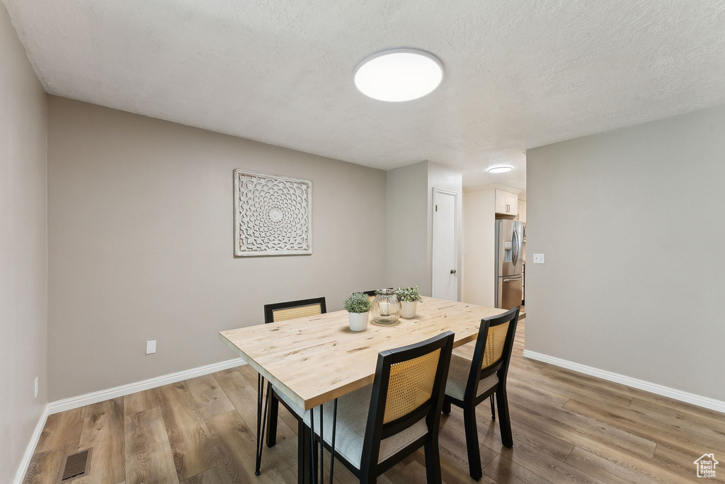 Dining area featuring light wood-type flooring, baseboards, and a textured ceiling
