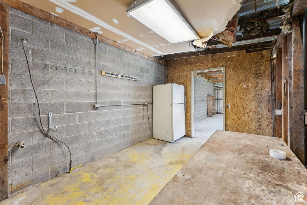 Below grade area with freestanding refrigerator and concrete block wall