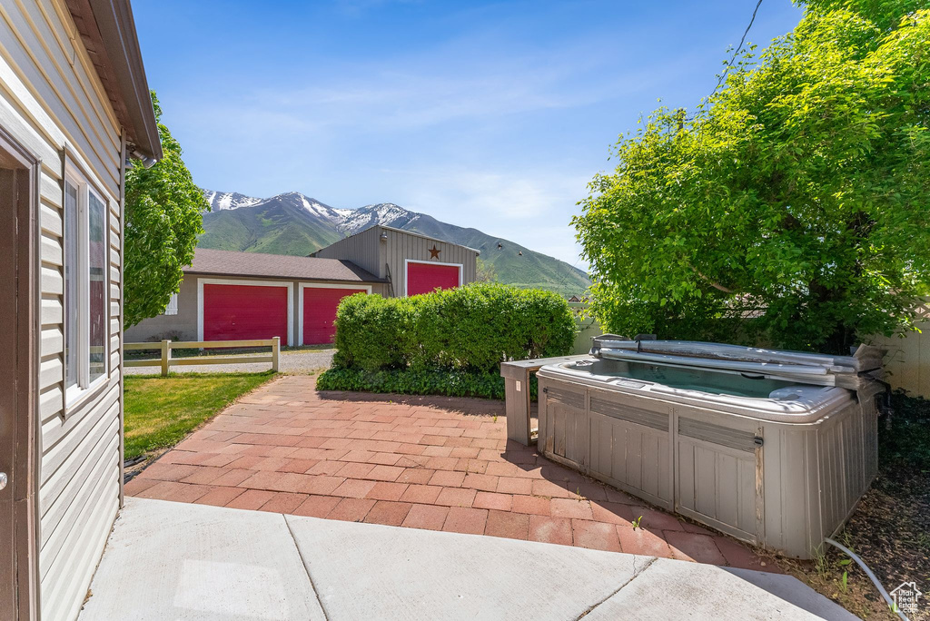 View of patio featuring a mountain view, a hot tub, fence, and an outdoor structure