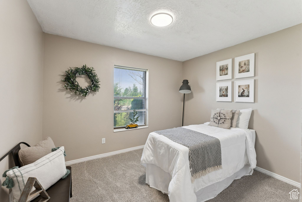 Carpeted bedroom featuring baseboards and a textured ceiling