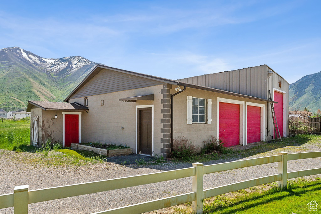 View of front of house featuring concrete block siding, fence, a mountain view, and a garage