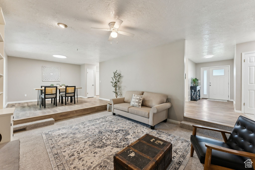 Living area featuring a ceiling fan, a textured ceiling, and baseboards