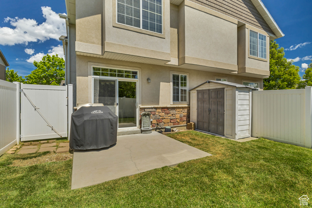 Back of house featuring stucco siding, a gate, a storage shed, an outbuilding, and a patio