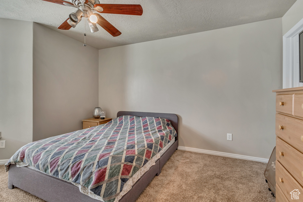 Bedroom with carpet flooring, baseboards, a textured ceiling, and a ceiling fan