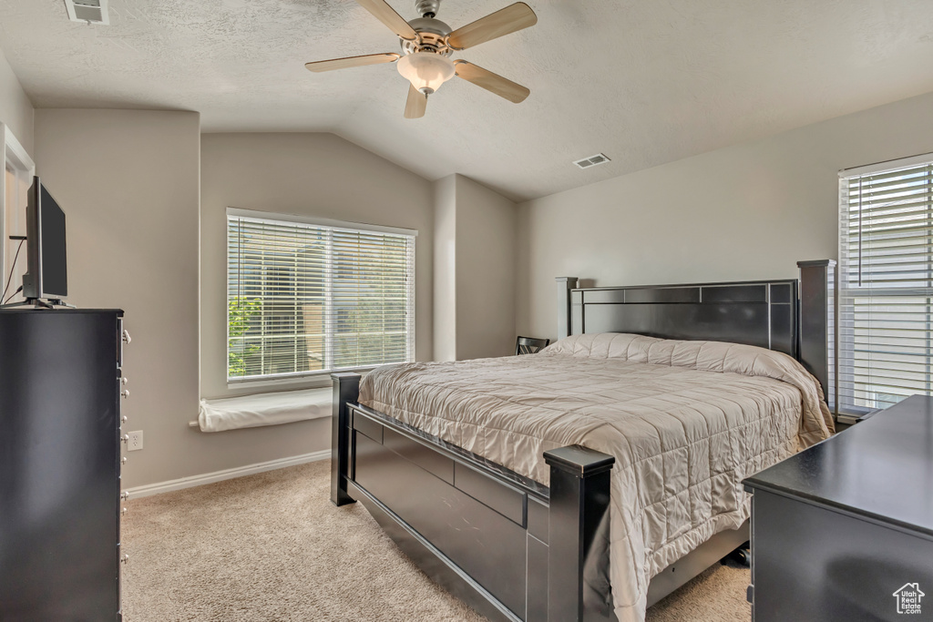 Bedroom with light colored carpet, vaulted ceiling, baseboards, and a ceiling fan