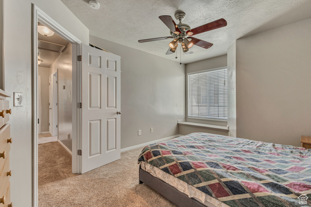 Carpeted bedroom with a textured ceiling, ceiling fan, and baseboards