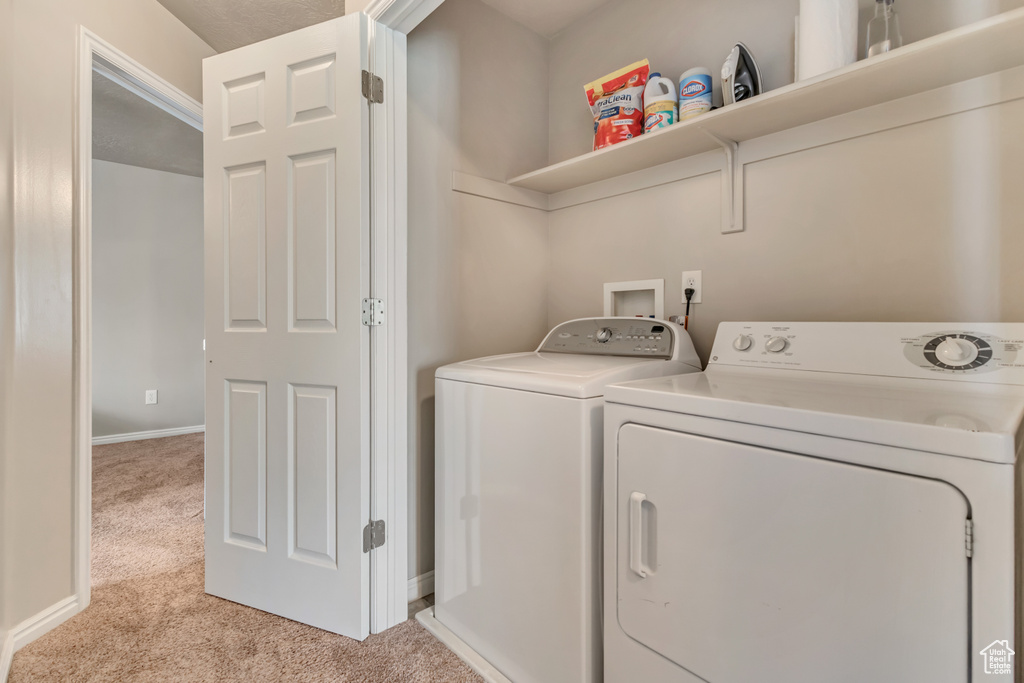 Laundry room featuring light carpet, separate washer and dryer, and baseboards