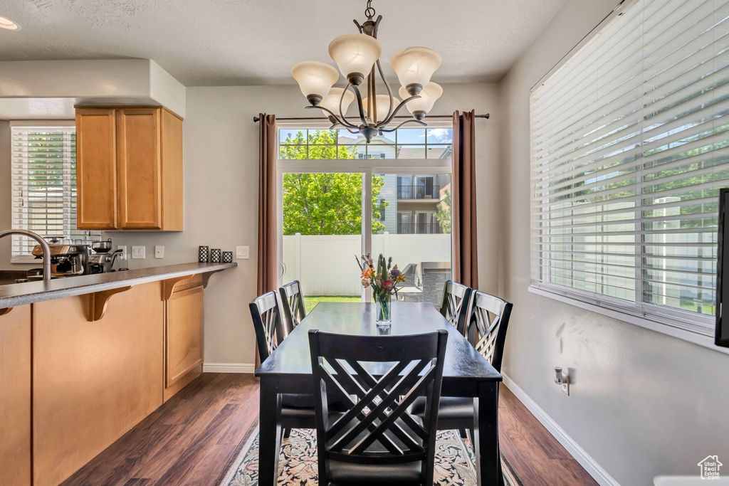 Dining room with dark wood-style flooring, healthy amount of natural light, and a chandelier