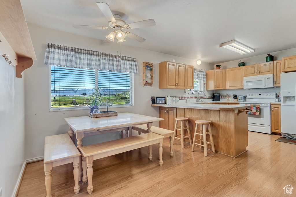 Kitchen featuring white appliances, light brown cabinetry, light countertops, and light wood-style floors