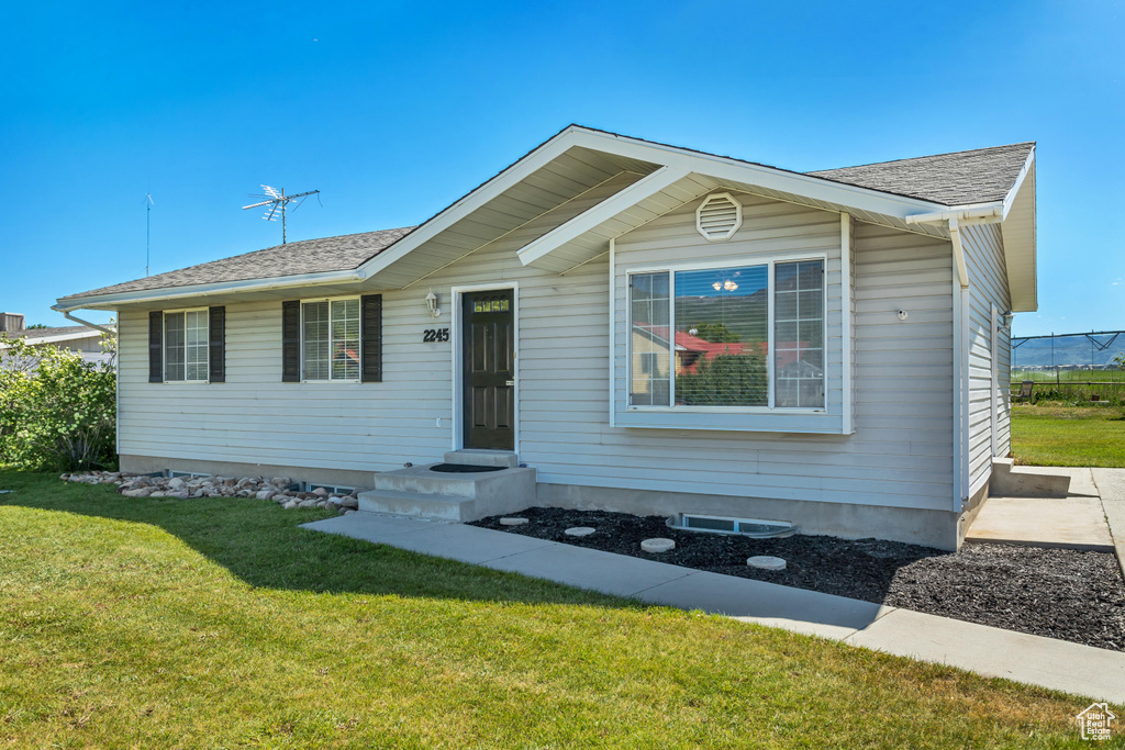 View of front facade featuring a front yard and a shingled roof