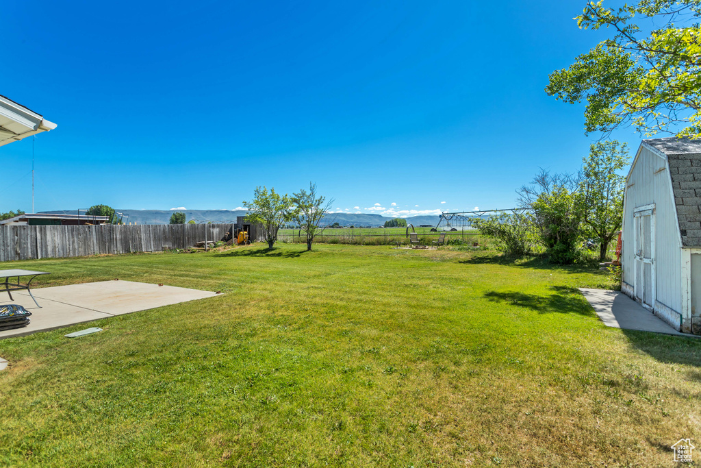 View of yard featuring a patio area, a shed, an outbuilding, and a mountain view