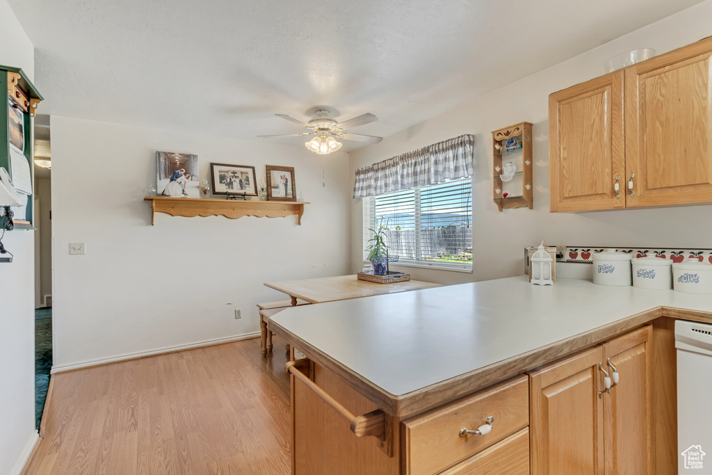 Kitchen featuring white dishwasher, ceiling fan, light wood finished floors, a peninsula, and light countertops