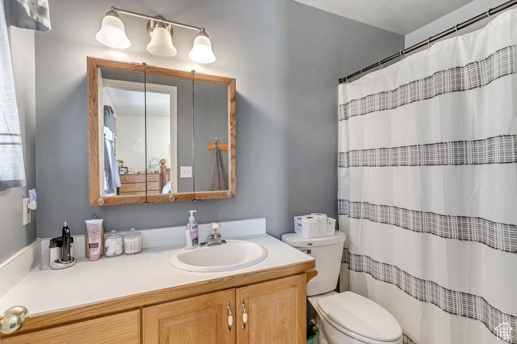 Bathroom featuring toilet, vanity, and curtained shower