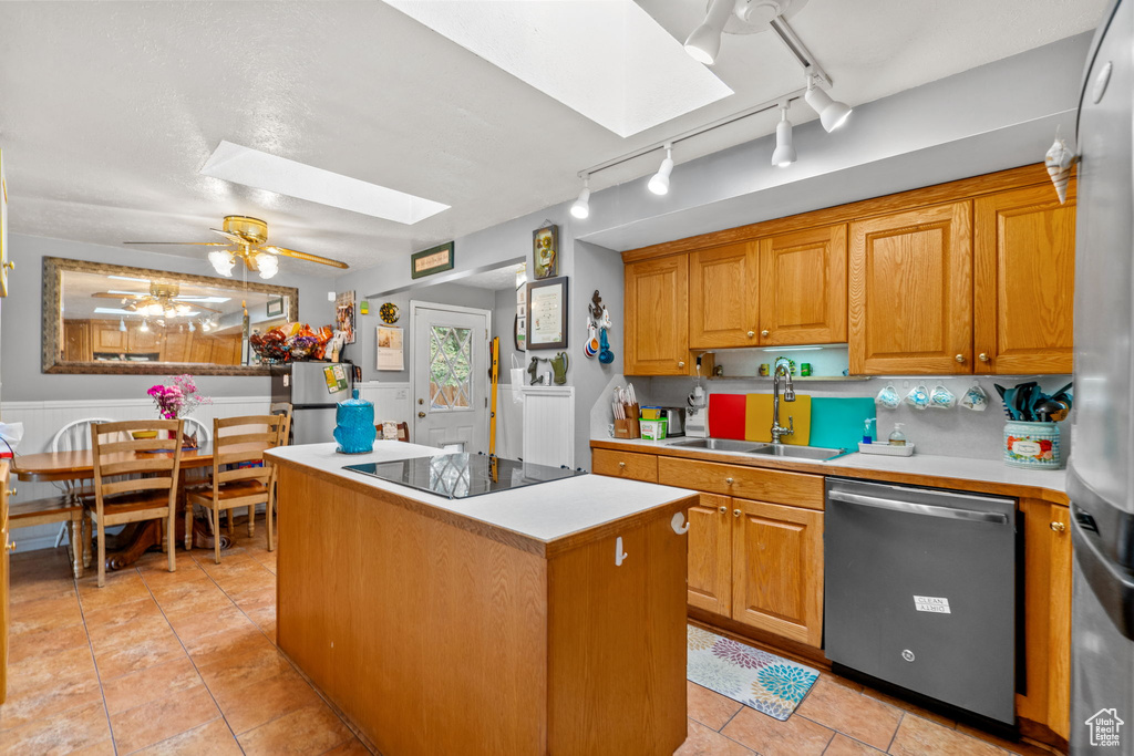 Kitchen with stainless steel appliances, a sink, a skylight, a kitchen island, and rail lighting