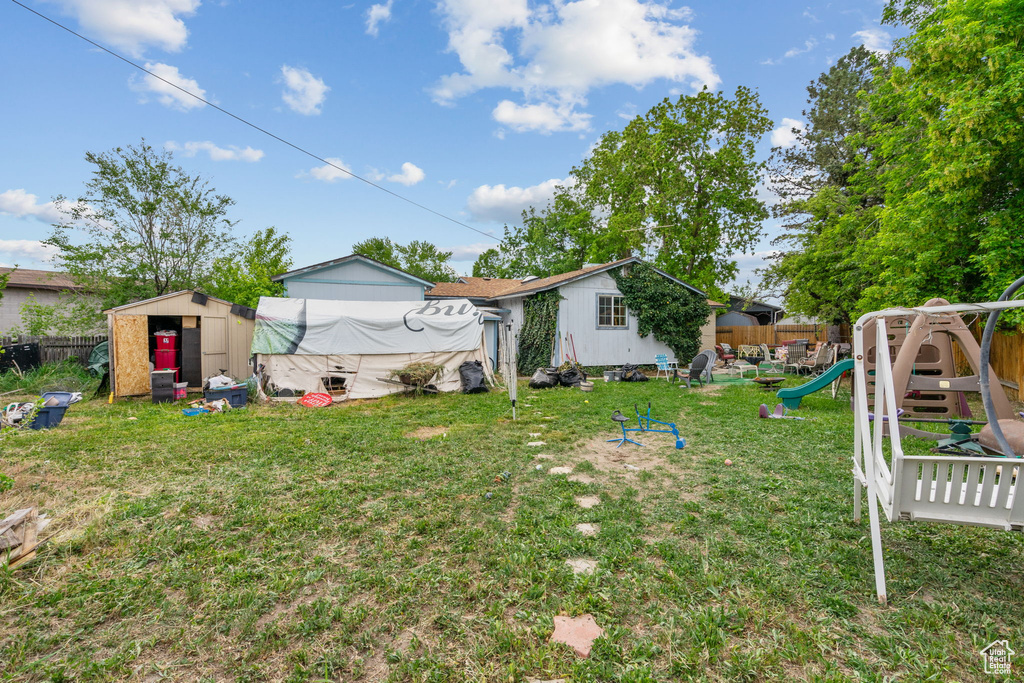 View of yard featuring a playground, a shed, and an outbuilding