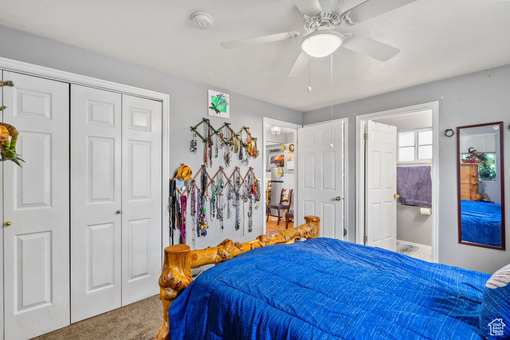 Carpeted bedroom with ceiling fan, a closet, and ensuite bathroom