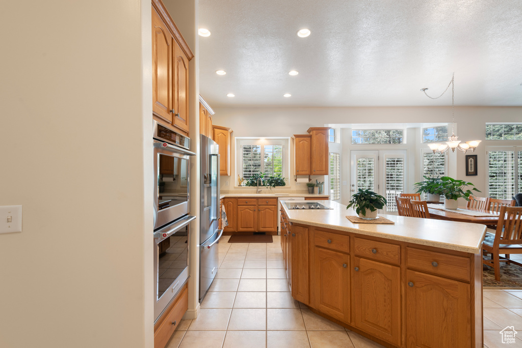 Kitchen featuring appliances with stainless steel finishes, a kitchen island, recessed lighting, healthy amount of natural light, and light countertops