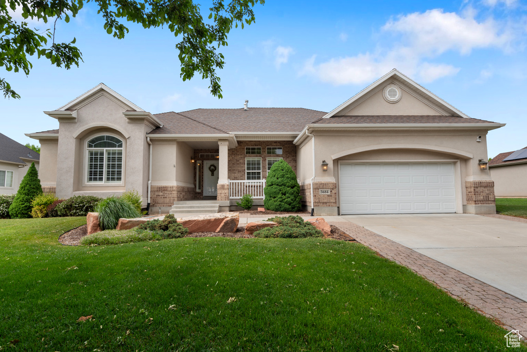 View of front of house featuring concrete driveway, a front lawn, stucco siding, a garage, and brick siding