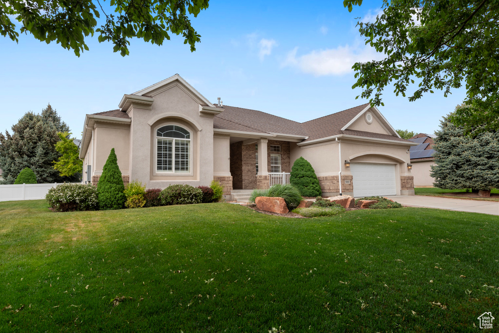 View of front facade with stucco siding, driveway, a garage, and covered porch