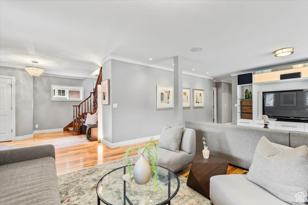 Living area with crown molding, light wood-type flooring, stairway, baseboards, and recessed lighting
