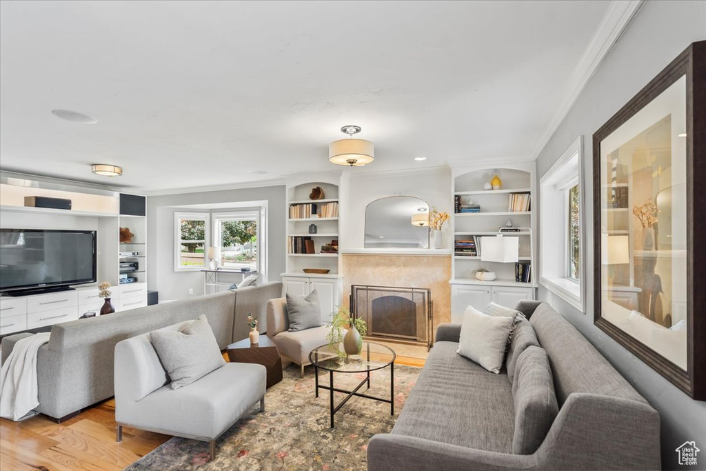 Living area featuring ornamental molding, wood finished floors, a high end fireplace, and built in features
