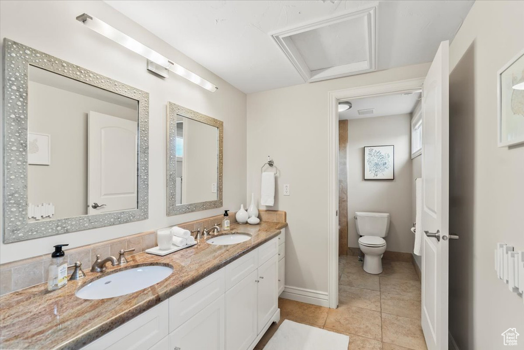 Bathroom with tile patterned flooring, double vanity, toilet, and baseboards