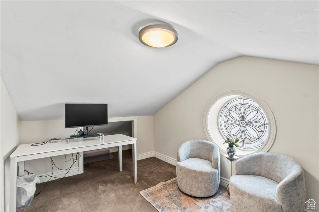 Carpeted office space featuring lofted ceiling and baseboards