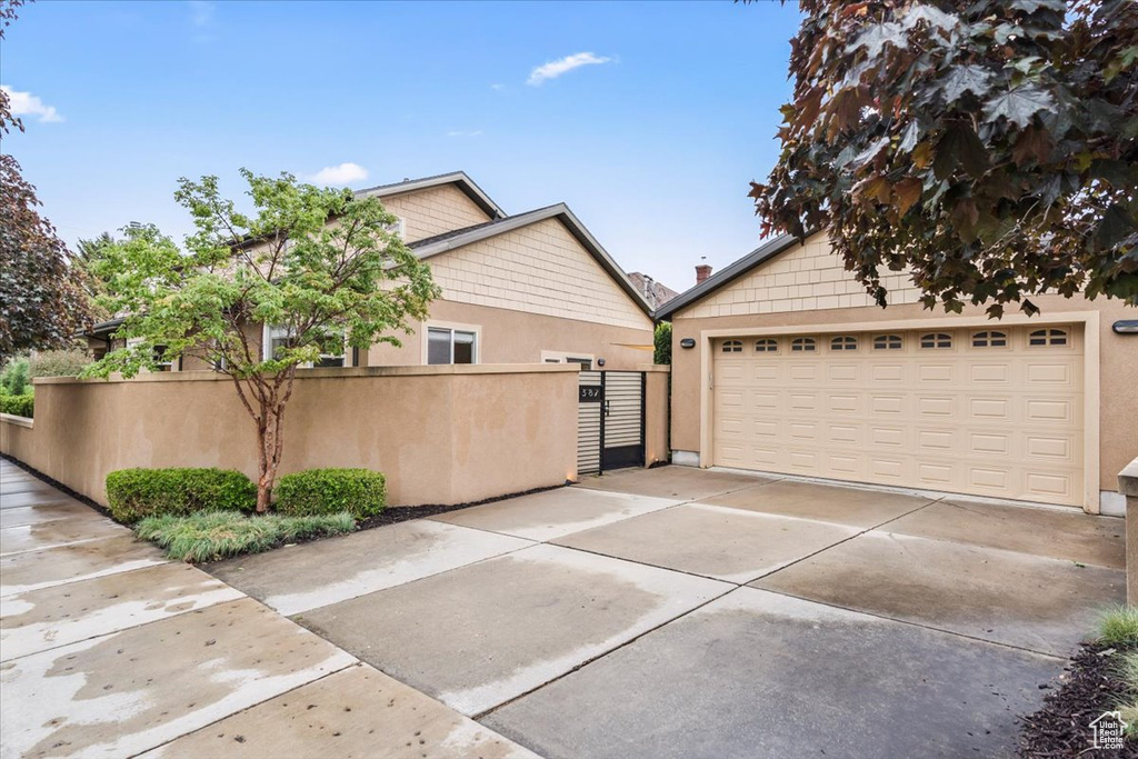 View of home's exterior featuring stucco siding, fence, a garage, and a gate