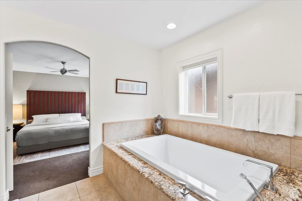 Ensuite bathroom with ceiling fan, tile patterned floors, and a garden tub