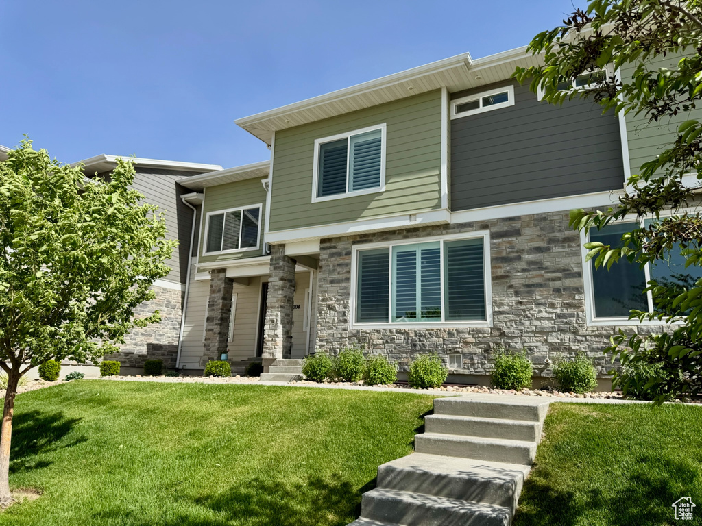 View of front of house featuring a front yard and stone siding