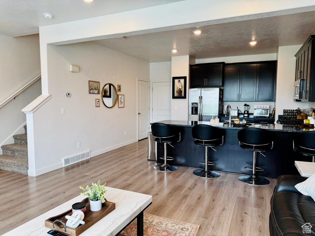 Kitchen with appliances with stainless steel finishes, a kitchen bar, a peninsula, light wood-style flooring, and recessed lighting