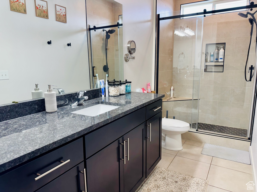 Bathroom featuring a stall shower, tile patterned floors, vanity, and toilet