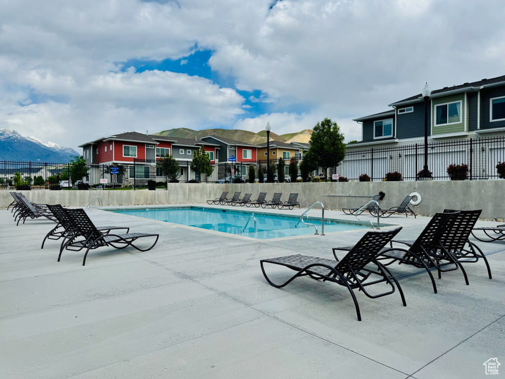 Community pool with fence, a patio area, a residential view, and a mountain view